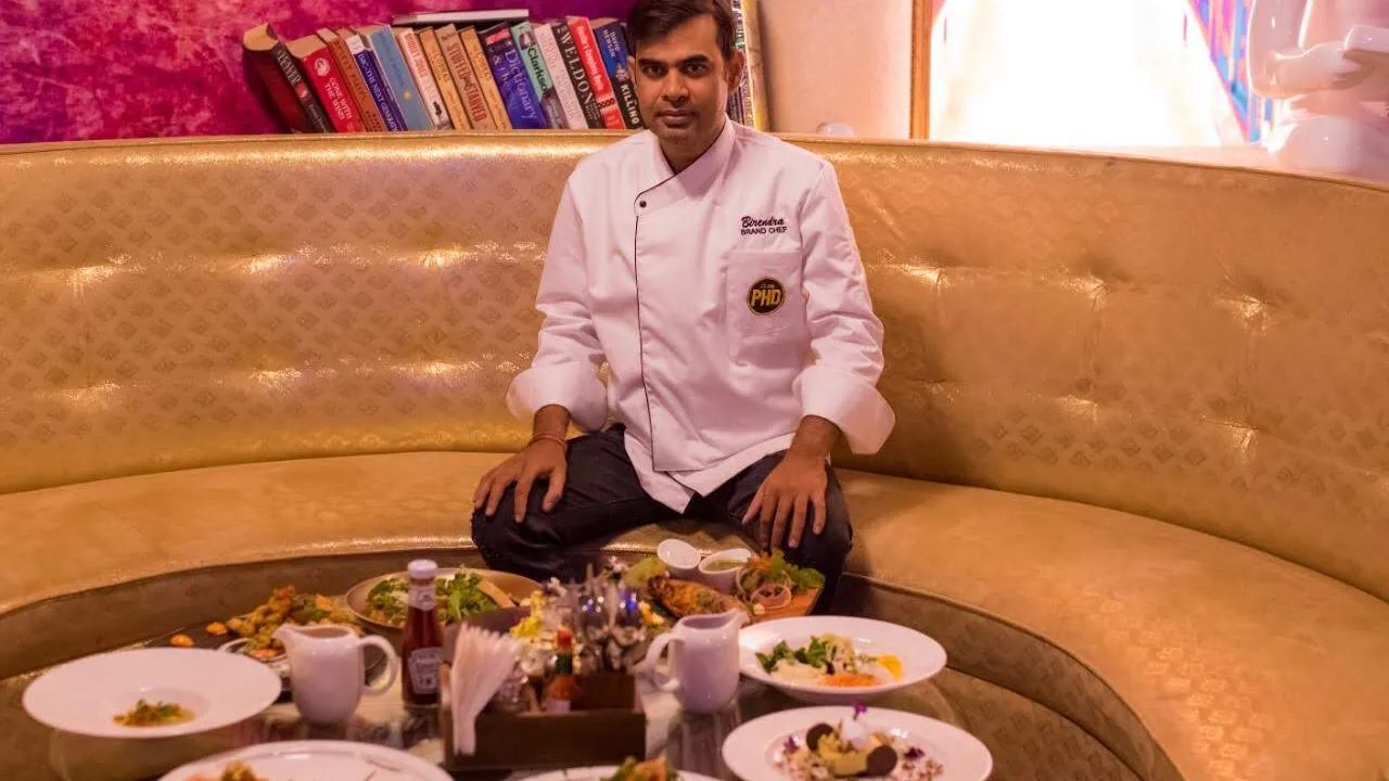Chef Birendra Singh at a food tasting with a table of plated dishes
